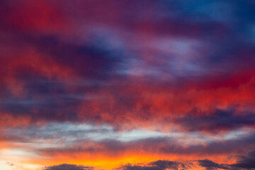 Fototapeta premium Vibrant orange and red clouds stretch across a dark blue sky