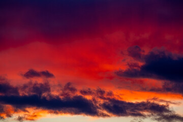 Fototapeta premium Vibrant orange and red clouds stretch across a dark blue sky
