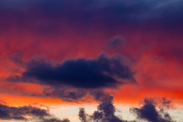 Fototapeta premium Vibrant orange and red clouds stretch across a dark blue sky