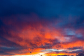 Obraz premium Fiery sunset colors illuminate soft atmospheric layers against a deep twilight backdrop