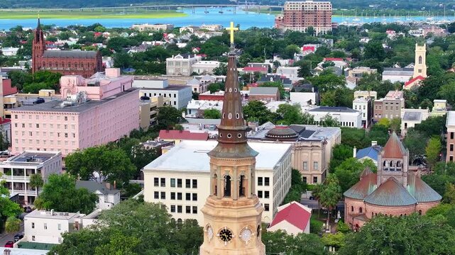 Panoramic aerial view of St. Philip's Church steeple and surrounding downtown Charleston, South Carolina skyline cityscape landscape with bay water and city landmarks in the distance - 4K Drone