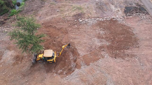 High angle aerial drone view of a heavy duty hydraulic earth excavator operating at a construction site near Pune India.