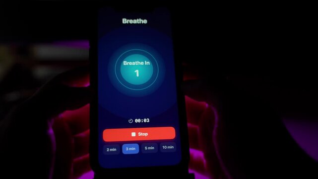 A user starts breathing exercises on a mobile app in a dark room. Emotion control techniques