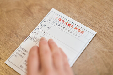 介護保険被保険者証を持つシニア女性の手元