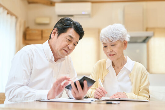 家計の計算をするアジア人シニア夫婦