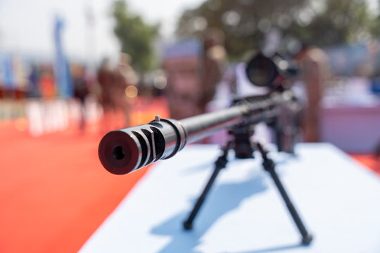 A close-up view of a rifle mounted on a bipod during a public display