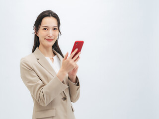 スマホ、スマートフォン、女性、笑顔、SNS、アプリ、検索、キャンペーン、セール、通販、ビジネス、メール、ビジネスパーソン、ビジネスウーマン、スーツ、楽しみ、期待、コピースペース、通信、DX、デジタル、IT、仕事、白バック、プレゼント、ポイント、日本人、キャリアウーマン、携帯電話、転職、タッチ、操作、金融、上半身、爽やか、会社員、30代、20代、若い、モバイル、動画、投稿、撮影、カメラ、人材、紹介、 © metamorworks