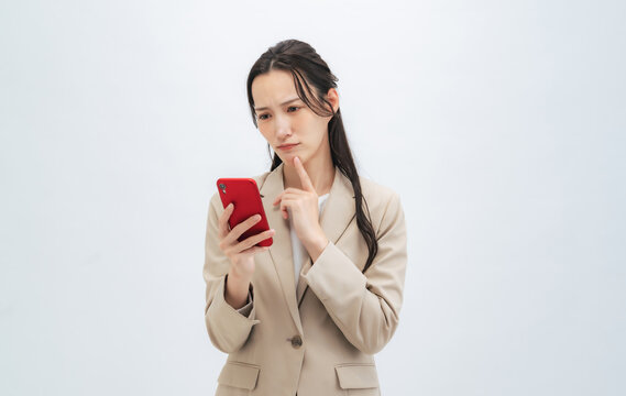 スマホ、スマートフォン、悩む、女性、不満、ビジネスパーソン、ビジネスウーマン、SNS、トラブル、炎上、メール、検索、問題、考える、悩み、困る、疑問、心配、不安、落ち込む、ストレス、イライラ、がっかり、残念、故障、電波障害、クレーム、エラー、失敗、後悔、ネガティブ、オークション、切り抜き、白バック、コピースペース、悲しい、ニュース、アプリ、マッチング、日本人、ビジネス、スーツ、全身、会社員、仕事、ナ