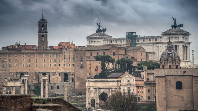 Ancient ruins of the Roman Forum and Vittoriano monument under a dramatic stormy sky, Rome, Italy
