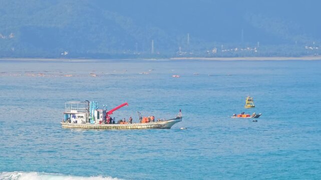Small working fishing boats and utility vessels anchored along Hualien coastline, calm blue waters and traditional maritime livelihood scene under clear coastal sky in eastern Taiwan
