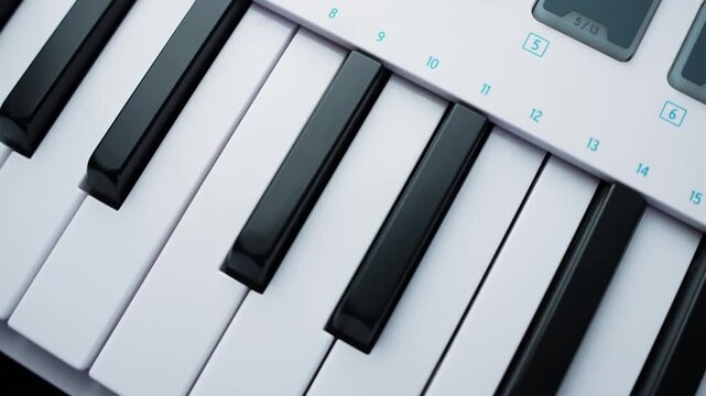 Close-up of a MIDI keyboard controller with piano keys on a desk, shallow depth of field. Modern music production concept for composing, recording, and studio workflow.