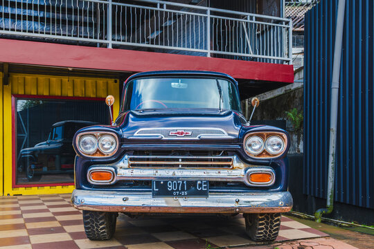Vintage Blue Chevrolet Apache Pickup Truck Parked in Front of a Modern Container Building