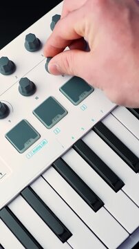Vertical close-up of a hand playing notes on a white MIDI keyboard controller with shallow depth of field, ideal for music production, songwriting, and studio b-roll.