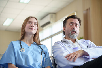 Obraz premium Experienced male doctor and young female nurse listening seminar together