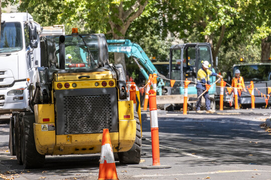 Road construction work in progress on an urban street with a road roller and workers in safety gear installing new asphalt. Urban maintenance and infrastructure improvement in Australia