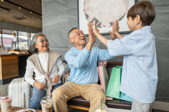 Senior asian happy grandparents playing with little grandson at cafe with luggage, Wealthy retirement lifestyle, family legacy, child education fund, intergenerational wealth and insurance concept