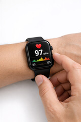 Fototapeta premium A hand touches a smartwatch displaying heart rate data on its screen, a blend of technology and sport