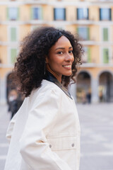 Young woman smiling turning head on urban street © Martí Rosselló