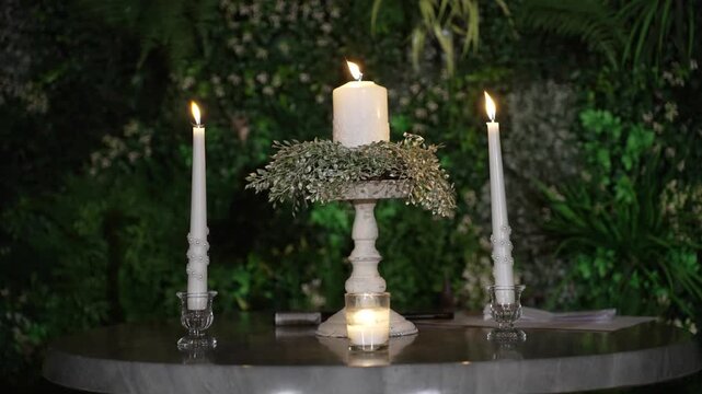 Atmospheric wedding venue setup with elegant table settings, glowing candles, and decorative lanterns creating a warm and romantic ambiance. Beautiful reception d cor prepared for guests, cozy evening