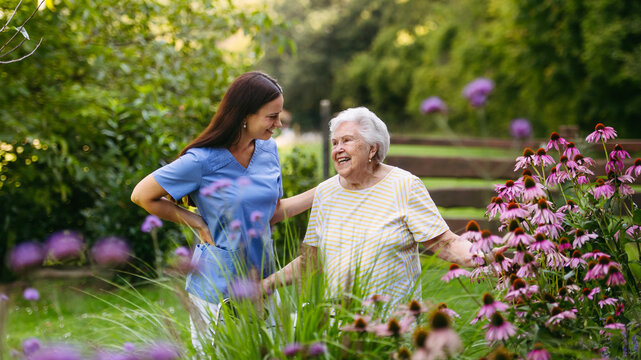 Home nurse spending time with elderly lady patient in garden.