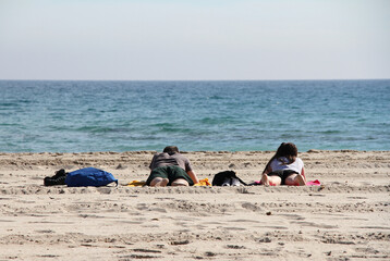 Pareja tumbada en toalla de playa disfrutando del sol del verano en vacaciones junto al mar