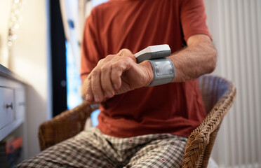 Senior man measuring blood pressure with wrist monitor.