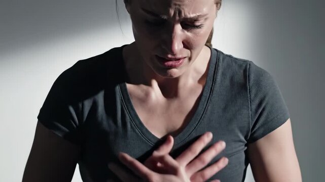 Woman clutching chest in pain, experiencing shortness of breath or heart attack symptoms