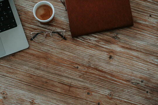 Vue de dessus d'un bureau rustique avec carnet ouvert, lunettes de vue et tasse de caf&eacute; 