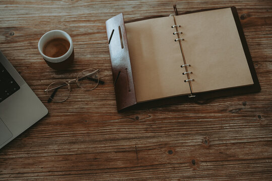 Vue de dessus d'un bureau rustique avec carnet ouvert, lunettes de vue et tasse de caf&eacute; 