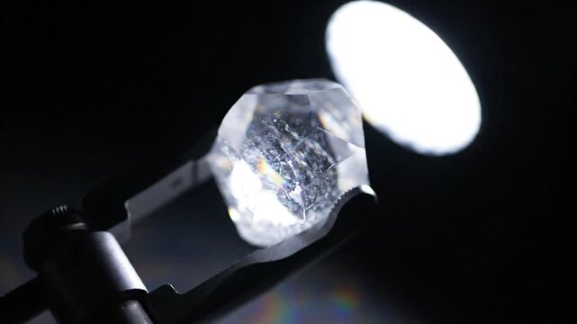 Close-up of a raw, uncut diamond sparkling under a spotlight, showcasing its facets and internal inclusions.