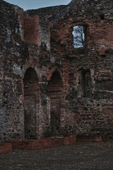 Obraz premium Exterior view of medieval castle ruins with high stone walls and arched openings. Historical architecture of a destroyed fortress reflecting centuries of European history and heritage.