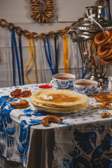Pancakes on the table next to the samovar and caviar