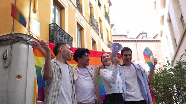 Cheerful group of friends with a rainbow flag celebrating at a gay pride parade. Slow motion footage of people celebrating sexual diversity