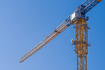 Fototapeta premium Tower crane against clear blue sky at construction site