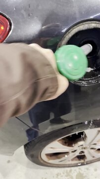 Gasolina derramada al repostar en coche con manguera de surtidor en gasolinera