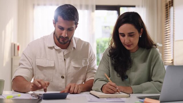Couple budgeting and calculating tax with laptop at home, managing finance and planning for longterm investment