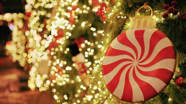 Christmas tree decorated with warm lights and a large red and white peppermint style ornament