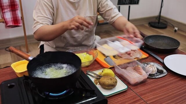 Close-up of hands seasoning cooked potatoes and grinding black pepper for homemade mashed potato meal