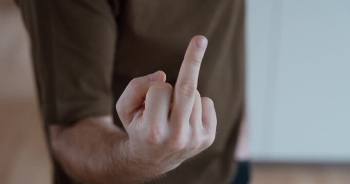 Close-up of a man making an obscene middle finger gesture toward the camera. Concept of anger, insult, rebellion, disrespect, provocation and rude behavior.