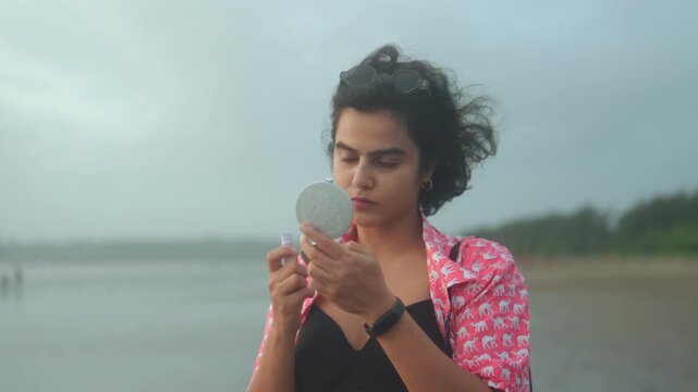 Candid outdoor video of woman looking into compact mirror by the seaside