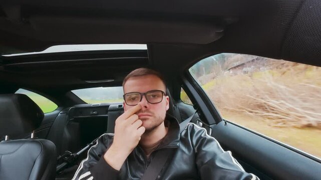 Interior car shot of a man picking his nose while driving. Concept of distraction, bad habits, careless behavior and road safety risk.