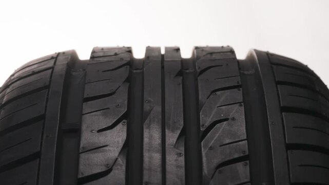 Car Tire Tread Ornament. New car wheel close-up slowly spinning showing tread pattern on white background