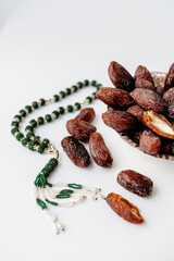 Obraz premium Minimalistic flat lay for Ramadan with a bowl of dates for iftar and green prayer beads