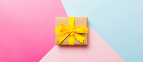Obraz premium holiday paper present tied yellow ribbon bow top view with copy space. Flat lay holiday background. Birthday or christmas present. Christmas gift box concept with copy space
