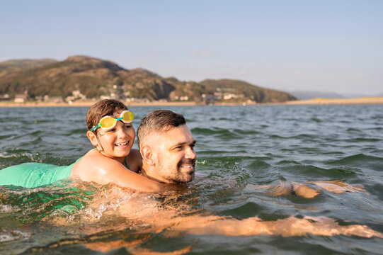 Father and daughter swimming together in coastal water.