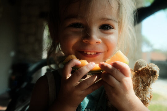 Smiling Toddler Eating Fresh Fruit in Natural Light