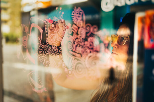 Eccentric female artist painting dribbles on art studio window
