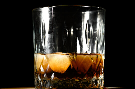 A glass of whiskey with ice cubes isolated on a black background