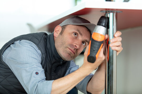 handyman using cordless drill for kitchen installation