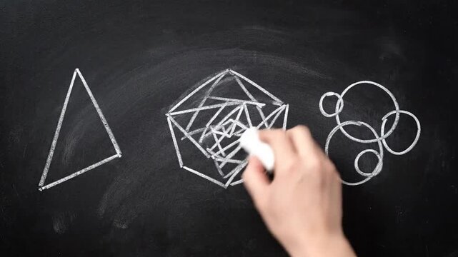Hand drawing geometric shapes and patterns on a chalkboard with chalk